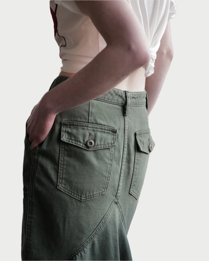 The image depicts a person wearing the white knotted t-shirt paired with Le Superbe's Very Mindful Skirt, featuring olive green color and vintage-inspired, cargo-style pockets.