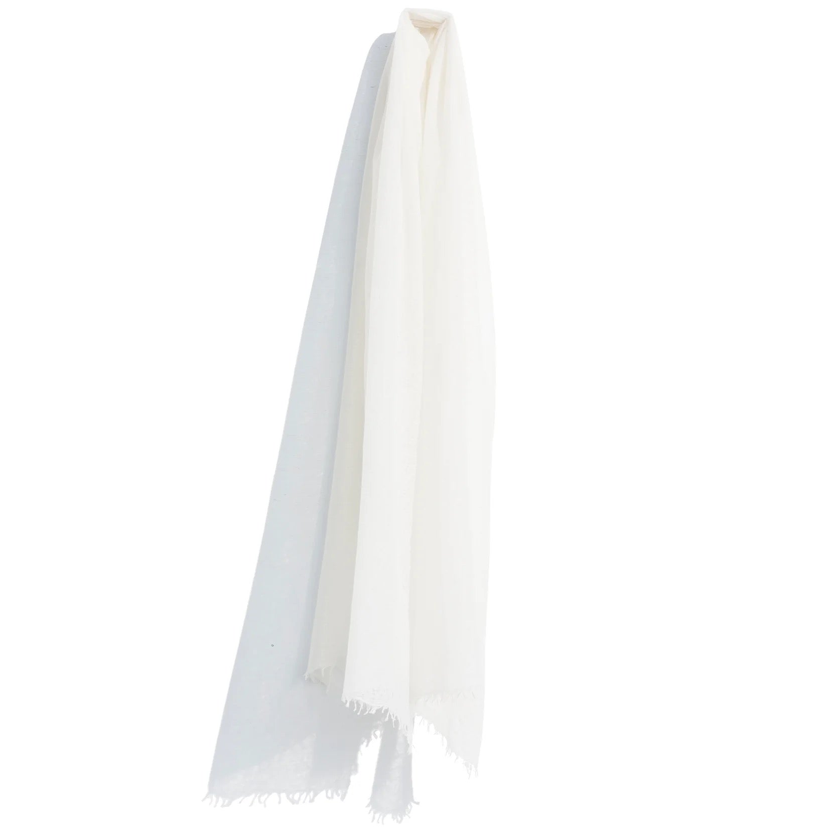 A white, lightweight Whisperweight Cashmere Scarf from Meg Cohen hangs against a plain white background. The edges of the scarf are slightly frayed, adding a subtle texture to its overall smooth appearance, showcasing the quality of natural fibers.