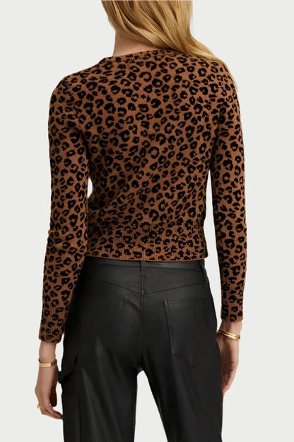 A person, draped in the elegant Baby Leopard Cardigan from SPRWMN, crafted with the richness of Mongolian Cashmere and paired with black pants, is captured from behind. Their long hair cascades effortlessly against a light background, creating a striking yet elegant silhouette.