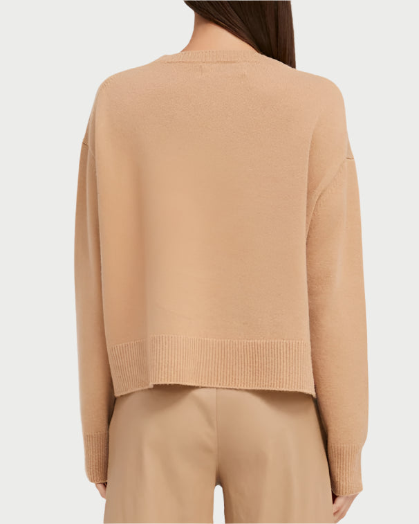 Rear view of a person wearing an ultra-soft SPRWMN Boxy Praline Cashmere Sweater and matching pants in beige. The monochromatic outfit has a relaxed fit with ribbed hems. Their long, straight brown hair cascades down their back.