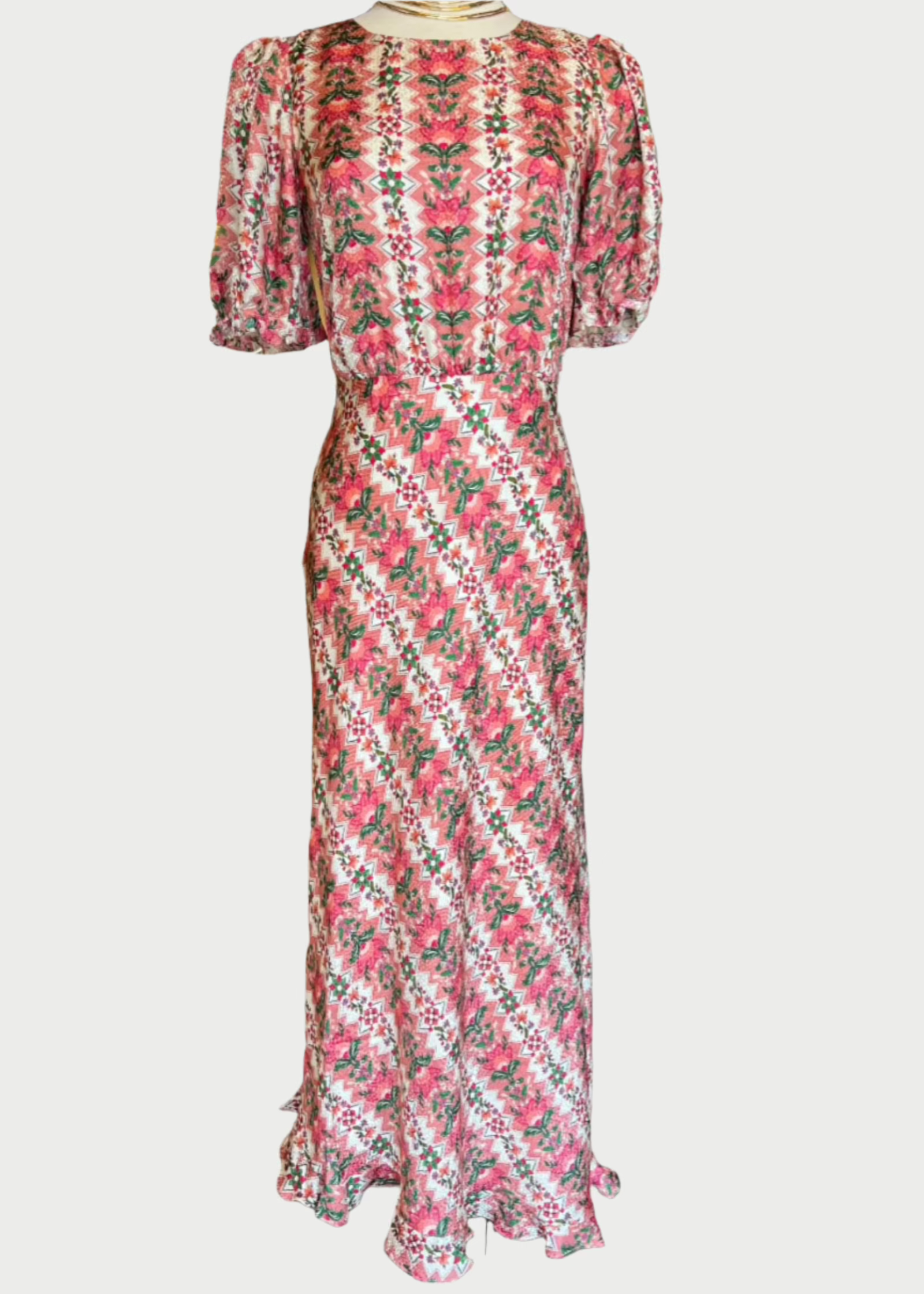 A full-length Saloni Vida-D Dress with a colorful floral pattern featuring pink, white, and green hues. The dress has puffed short sleeves, a high neckline, and a fitted waist. The straight long skirt flares slightly at the asymmetrical hem. Perfect for a WeddingGuest, the fabric appears lightweight and flowy.