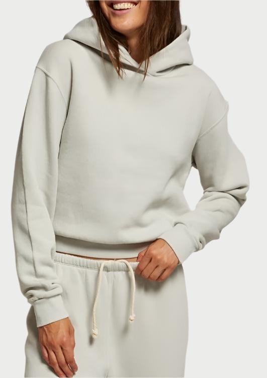 Wearing the Heart Hoodie in Chalk by perfectwhitetee, along with matching sweatpants, this individual radiates comfort and refined style. With a smile and one hand on their waist, the relaxed fit of the hoodie harmonizes beautifully with the drawstring waistband of their ensemble.