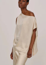 Load image into Gallery viewer, A person wearing an elegant, flowing One Shoulder Silk Top by Herskind and matching pants stands against a plain, light background. With a relaxed pose and a calm expression, they epitomize minimalist and sophisticated fashion in their 100% silk ensemble.
