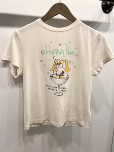 A white, relaxed fit Happys Classic Tee by RE/DONE hanging on a wooden hanger. The shirt features a cartoon dog with long ears sitting in a martini glass. The text above the dog reads "Happy's Bar," while the text below says, "We'll keep your spirits high." Made from ultra-soft cotton for maximum comfort.