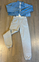 Load image into Gallery viewer, A button-up denim shirt is paired with the Dylan Classic Sweatpant in light gray, arranged on a wooden floor to display an elevated look. The sweatpants, designed by Les Tien, feature an elastic waistband with a white drawstring, and the shirt is laid out open with the sleeves extended.