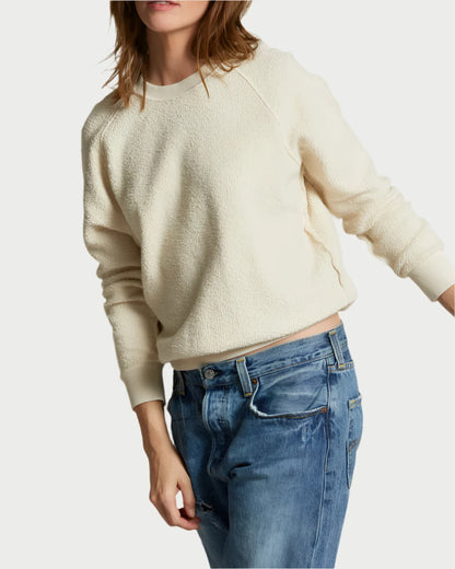 A person wearing the Ziggy Sweatshirt by perfectwhitetee, featuring a textured cream design with exposed seam detailing, along with blue jeans, posed against a plain light background. Their face is partially cropped out of the image.