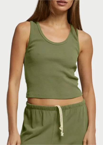 A woman with long, straight hair is wearing an olive-green Blondie Tank - Safari by perfectwhitetee and matching sweatpants with a white drawstring. She stands against a plain, light-colored background and looks directly at the camera, evoking a relaxed safari vibe.