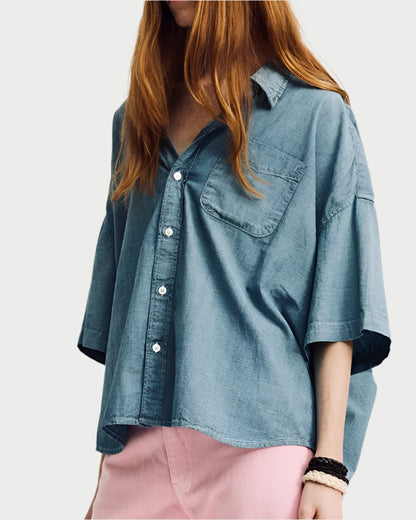 Wearing a Denimist SS Denim Shirt made from 100% cotton and styled with rolled sleeves and a chest pocket, the person has long red hair and pairs it with light pink pants against a plain white backdrop.