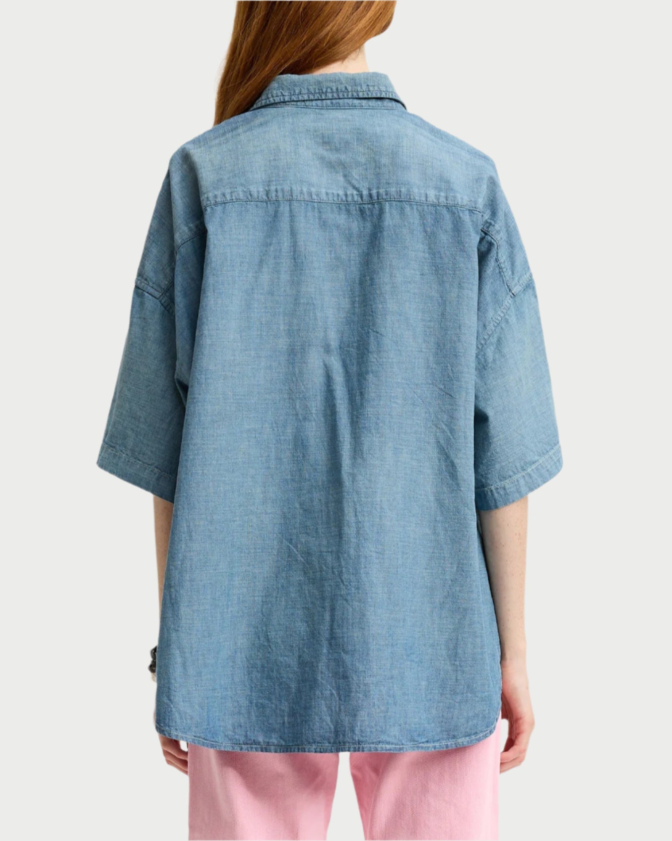 A person with long hair wears a Denimist SS Denim Shirt made of 100% cotton over pink pants, seen from the back against a light background.