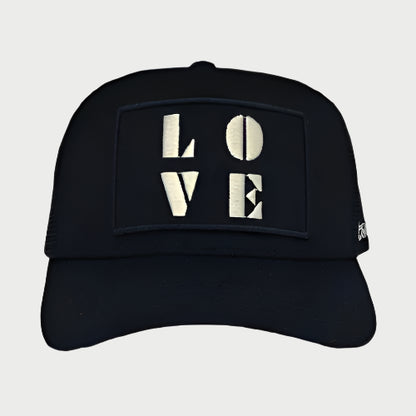 A Soulbyrd LOVE Trucker hat, featuring a black design with the word "LOVE" prominently embroidered in bold white letters on the front.