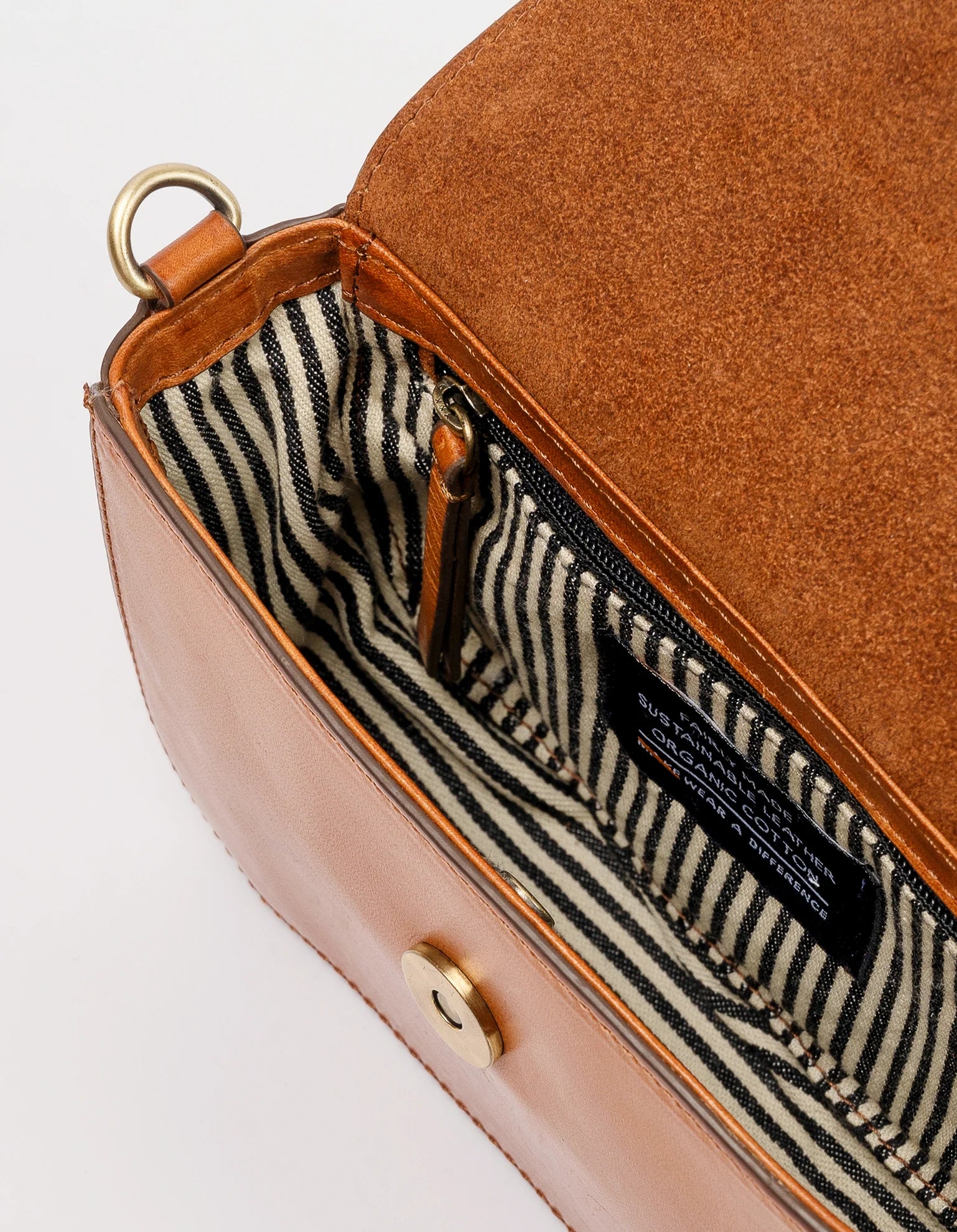 Discover the Cosmetic Bag In Cognac by O MY BAG, an open classic leather purse featuring a striped black and white fabric interior, ideal for travel-sized toiletries. It comes with a zipper pocket, a magnetic clasp, and a metal loop attached to the side.