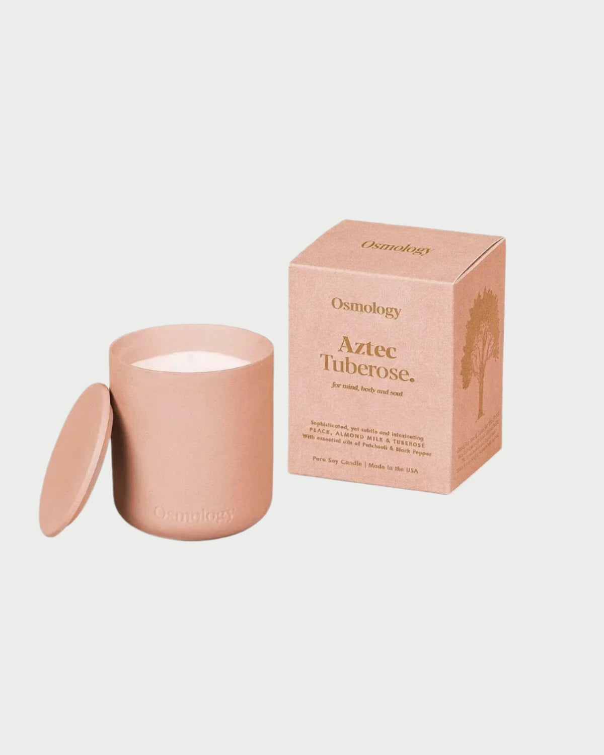 A pink Aztec Tuberose Candle from Osmology, made with plant-based wax, rests next to its matching pink box featuring a tree design, making it an excellent choice for aromatherapy enthusiasts.