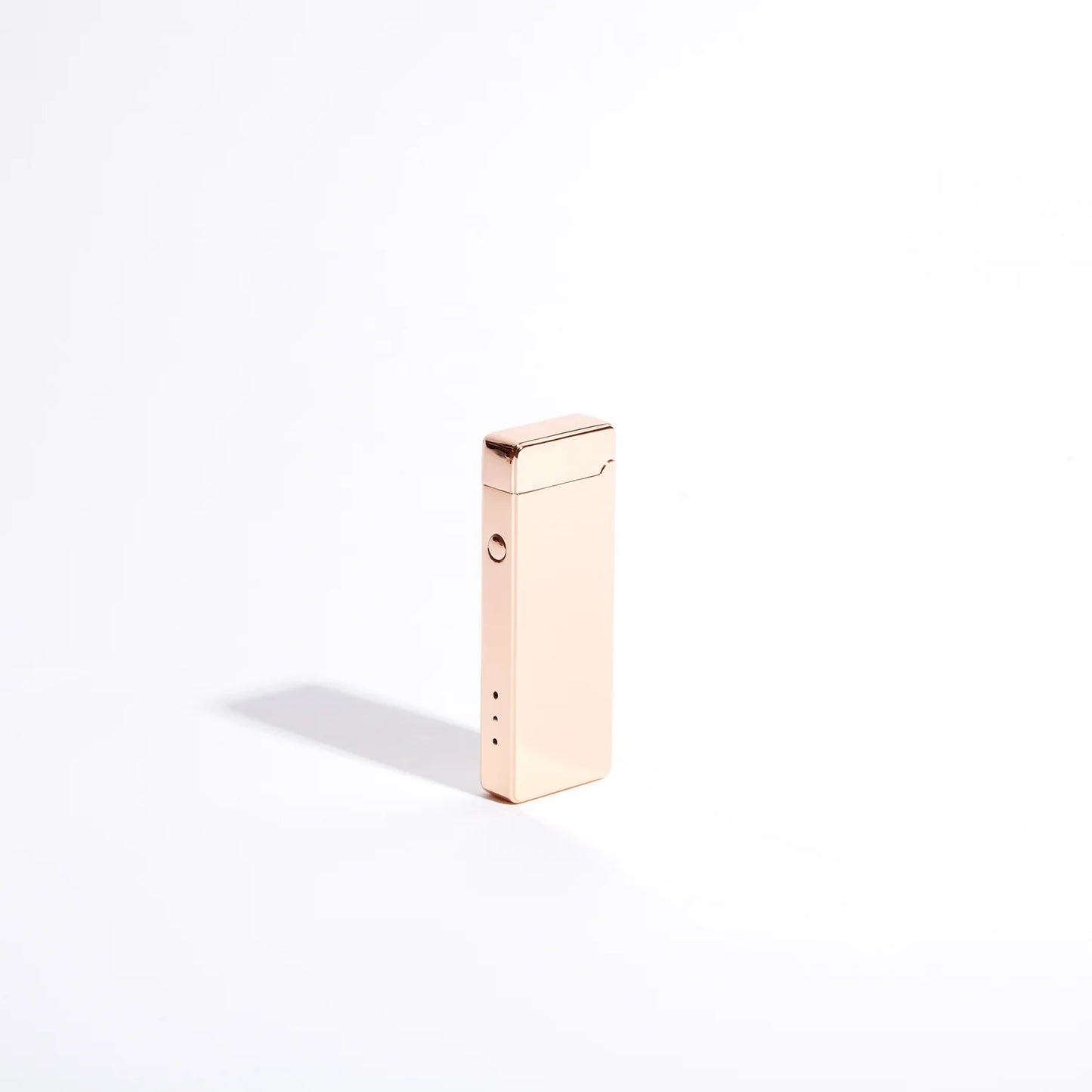 The Pocket USB Lighter from USB Lighter Co is a sleek, rectangular metallic lighter in a shiny rose gold hue, standing upright against a plain white background. Its windproof design and smooth surface catch the light, casting a gentle shadow to the left.