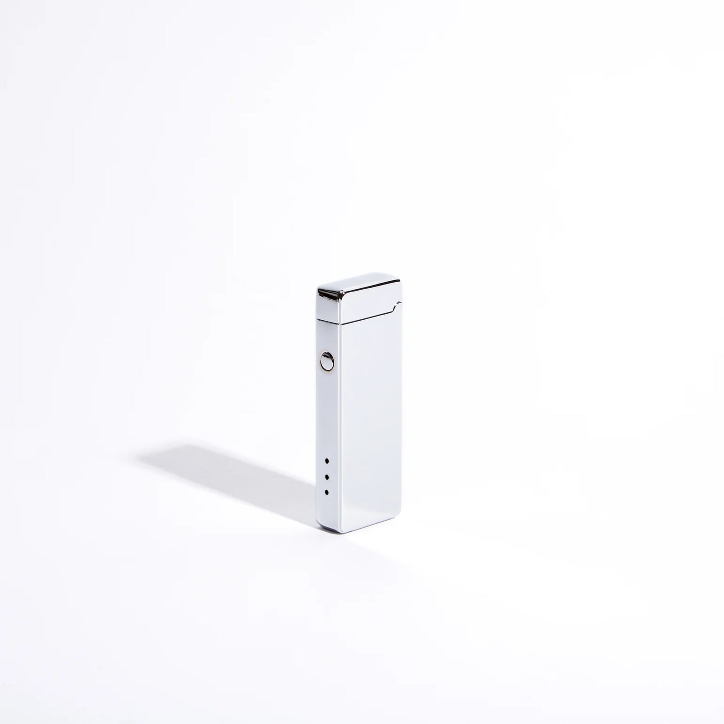 The Pocket USB Lighter from USB Lighter Co is a stylish rectangular silver device that stands upright against a plain white background. It resembles a rechargeable USB lighter and features a single button with three small indicator lights on the side.