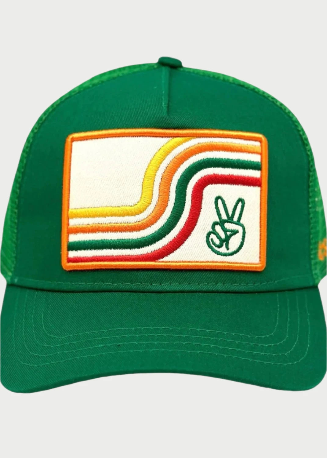 The Peace Trucker Hat from Soulbyrd is a green baseball cap featuring a mesh back and an embroidered front patch. The patch showcases retro-style curved lines in yellow, orange, and red, along with a peace symbol in the lower right corner, designed to evoke a sense of calm and mental clarity.