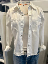 Load image into Gallery viewer, A mannequin is dressed in a RE/DONE Slim Denim Shirt layered over a white ribbed tank top. The outfit is paired with blue jeans, and the mannequin also wears a beaded necklace and a thin choker necklace. The display is set against a white background.