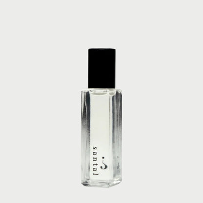 A clear rectangular bottle with a black cap from Riddle Oil exudes an exquisite fragrance. The label on this 8ml "Riddle Oil: Santal" perfume features a minimalist design on the lower part of the bottle, showcasing its sandalwood-infused santal scent against a pale gray background.