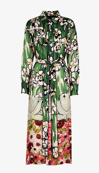 The Eco Vero-certified Tailored Shirt Dress by Smythe showcases a garden print with green leaves, white flowers, and red blossoms on a multicolored pattern. Its collar and belt complement the vibrant look of this long-sleeved floral shirtdress.