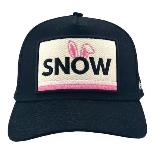 Introducing the Snow Bunny Trucker Hat by Soulbyrd: a black cap featuring a fabric patch on the front. The patch boldly displays the word "SNOW," with playful pink bunny ears adorning the "O" and a warm pink stripe underneath. Perfect for anyone who embodies the spirit of a SNOW bunny!