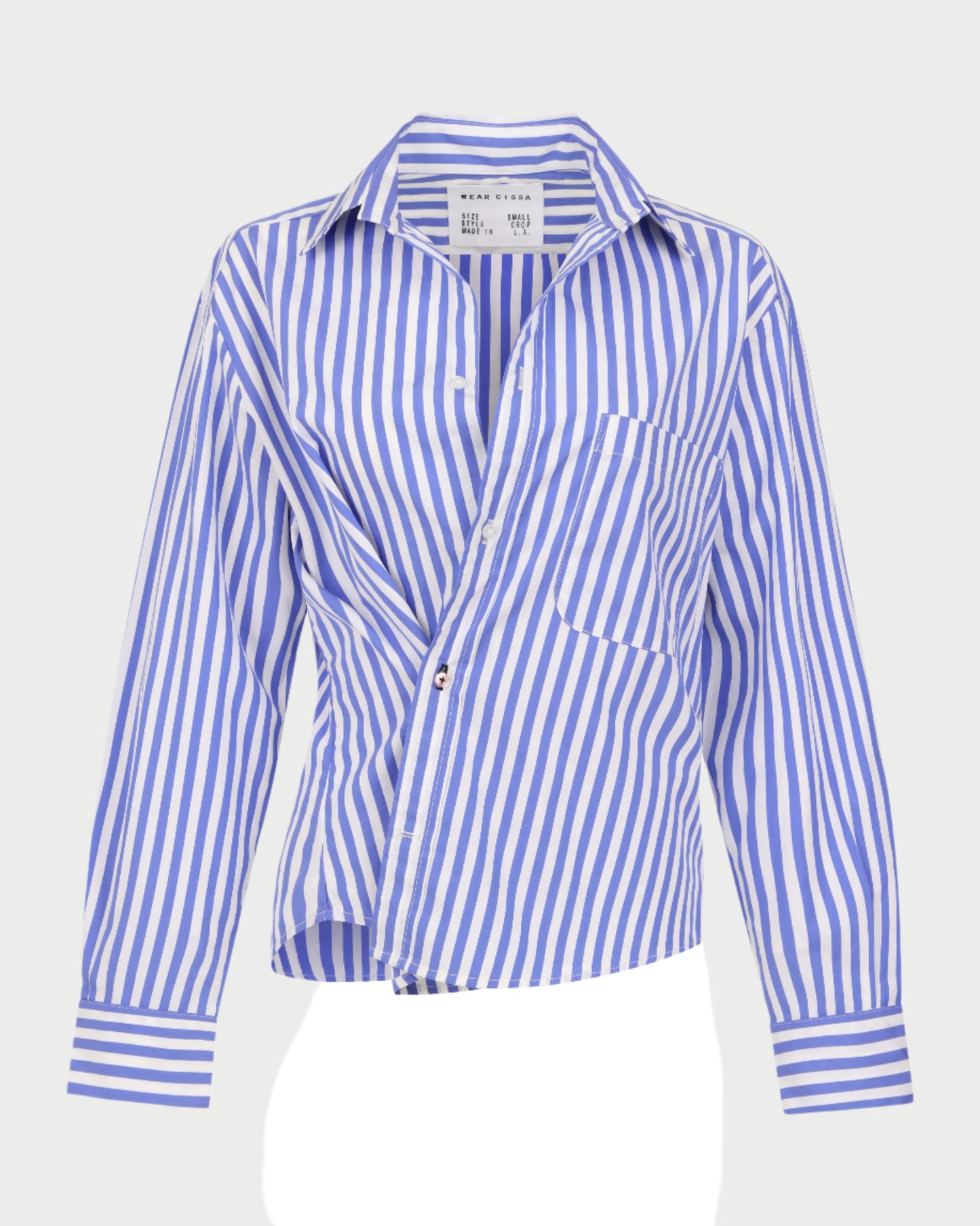 The Daily Shirt by WEAR CISSA is a men's blue and white vertically striped button-up made from luxurious Egyptian Cotton, featuring a collar and front pocket. The shirt has long sleeves and is slightly wrinkled against a light gray background.