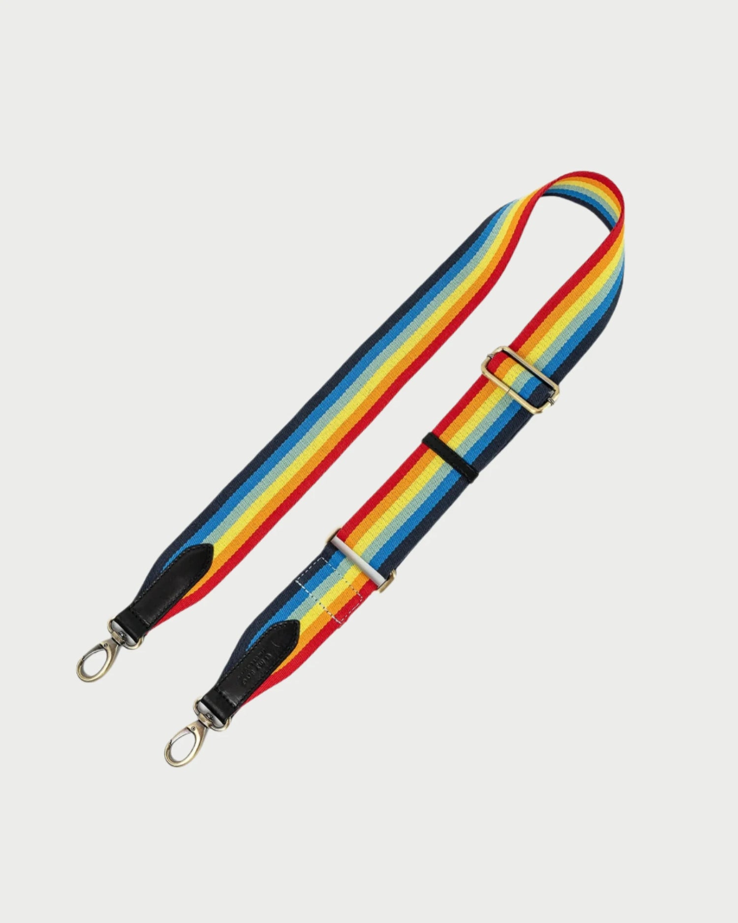 The O MY BAG Webbing Strap is a vibrant accessory showcasing alternating red, yellow, blue, and black stripes crafted with organic dyes. It includes metal clasps at both ends and an adjustable buckle in the middle, making it perfect for attaching to a bag.