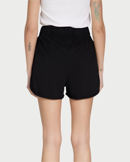 Rear view of a person in Les Tien's Scallop Short, featuring an elastic waistband. Paired with a white top, tattoos adorn both arms, creating a striking look against the light gray background; ideal for lounging in comfort and style.