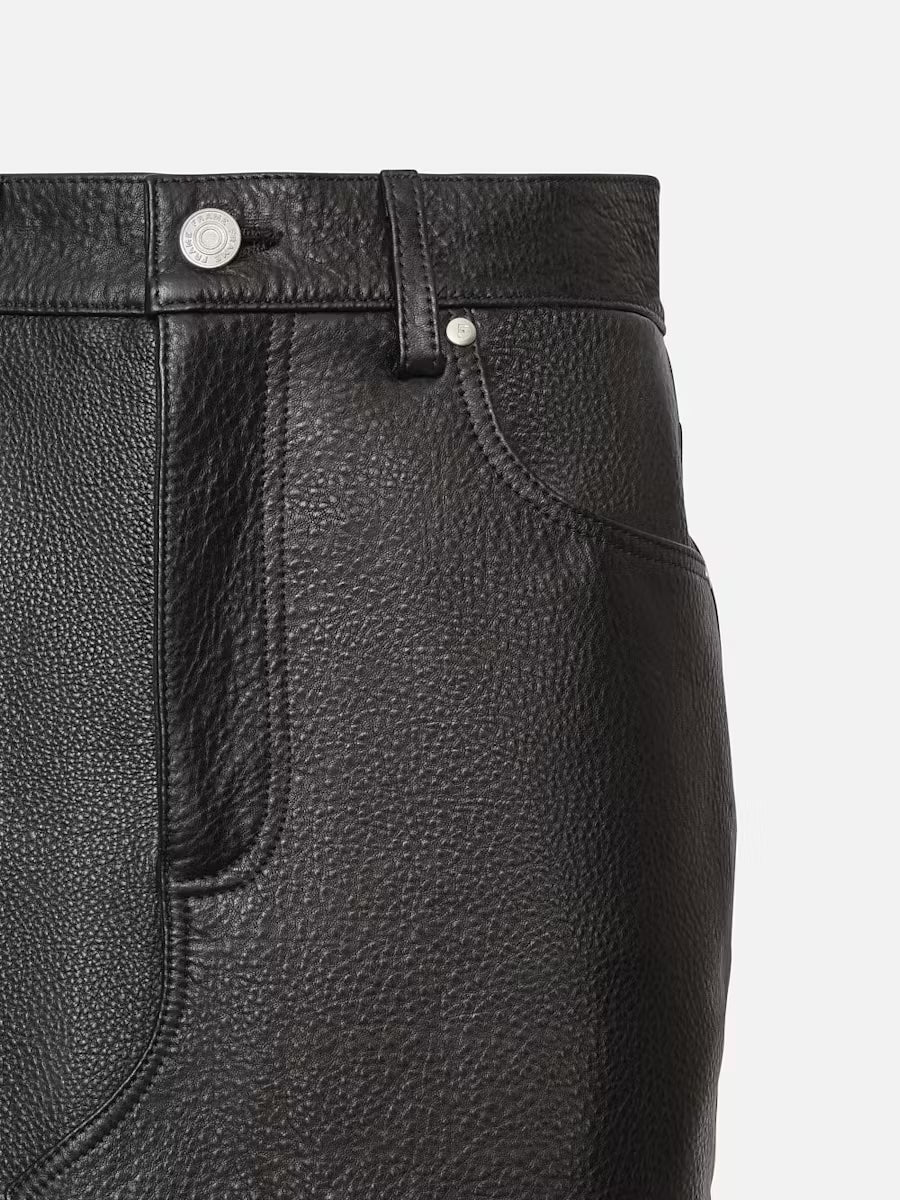 Close-up of a black lamb leather skirt by Frame featuring a textured finish. The image shows the upper part of the skirt, including a button and belt loop, with visible stitch detailing and a pocket.