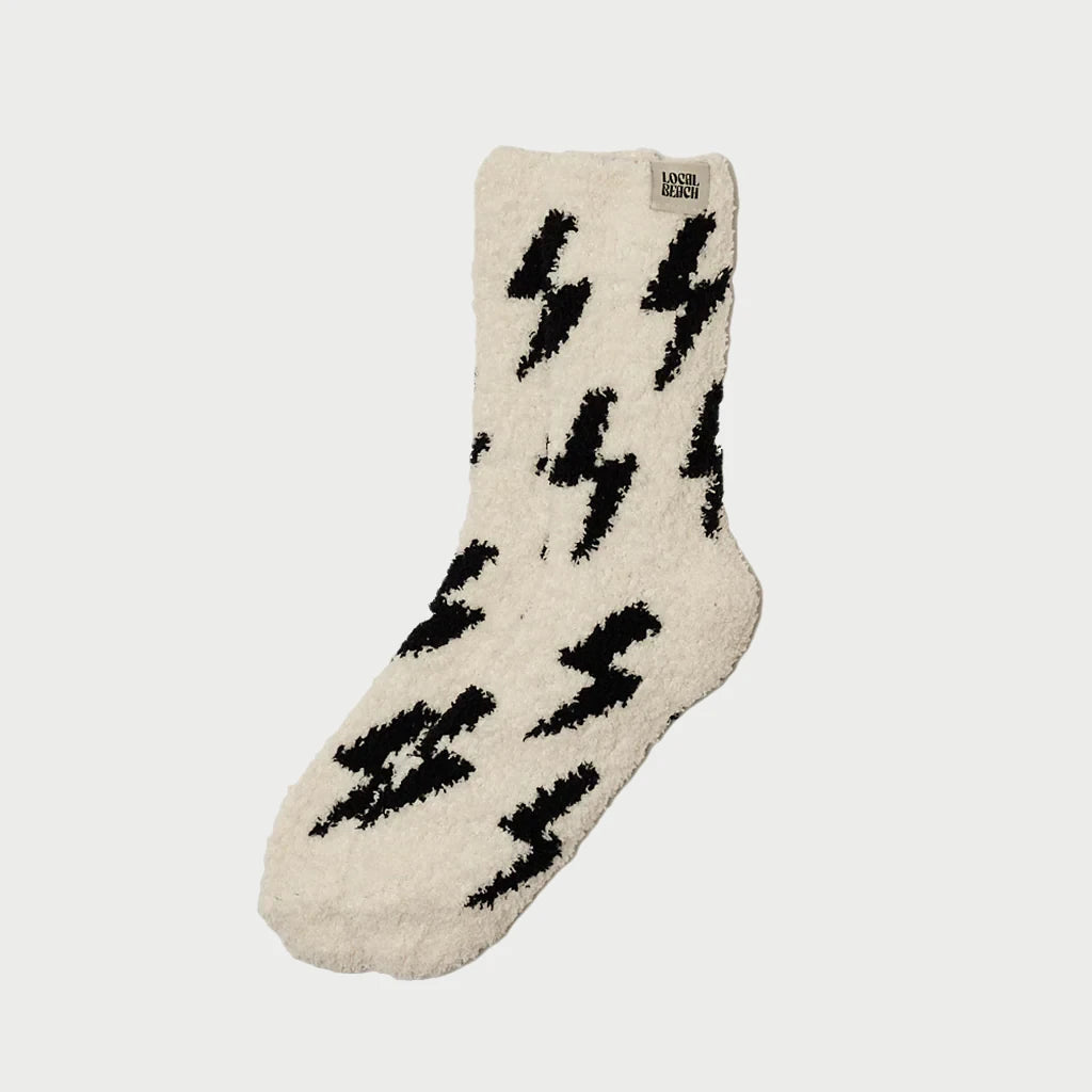 A single Cozy Sock by LOCAL BEACH is displayed against a white background, featuring a pattern of black lightning bolts. Crafted with Feather Knit construction, this sock offers a soft texture that promises warmth, making it a perfect addition to your cozy sock collection for cold weather.