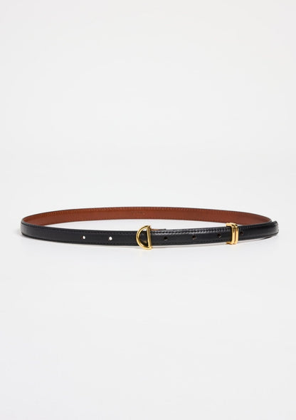 The Petit Crescent Belt by Frame, made from sleek black cowhide leather, boasts a small gold-tone buckle and a refined gold D-ring detail. The inner lining is brown. Laid flat against a white background, its understated elegance shines through.