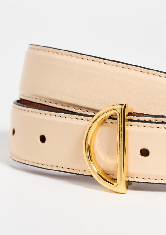 A close-up view of the Frame Crescent Belt, meticulously crafted from luxurious beige cowhide leather and adorned with a gold-tone, D-shaped buckle. This sophisticated belt features several small round holes for size adjustment and showcases visibly detailed stitching along the edges. The background is plain white.