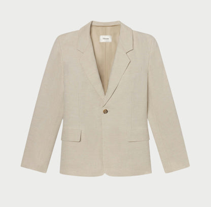 The Flax Grandfather Blazer by Frame is a light beige, single-button blazer featuring a notched lapel and two front flap pockets. This vintage-inspired piece offers classic charm with its straight, tailored cut for a woman's body, perfect for formal or semi-formal occasions.