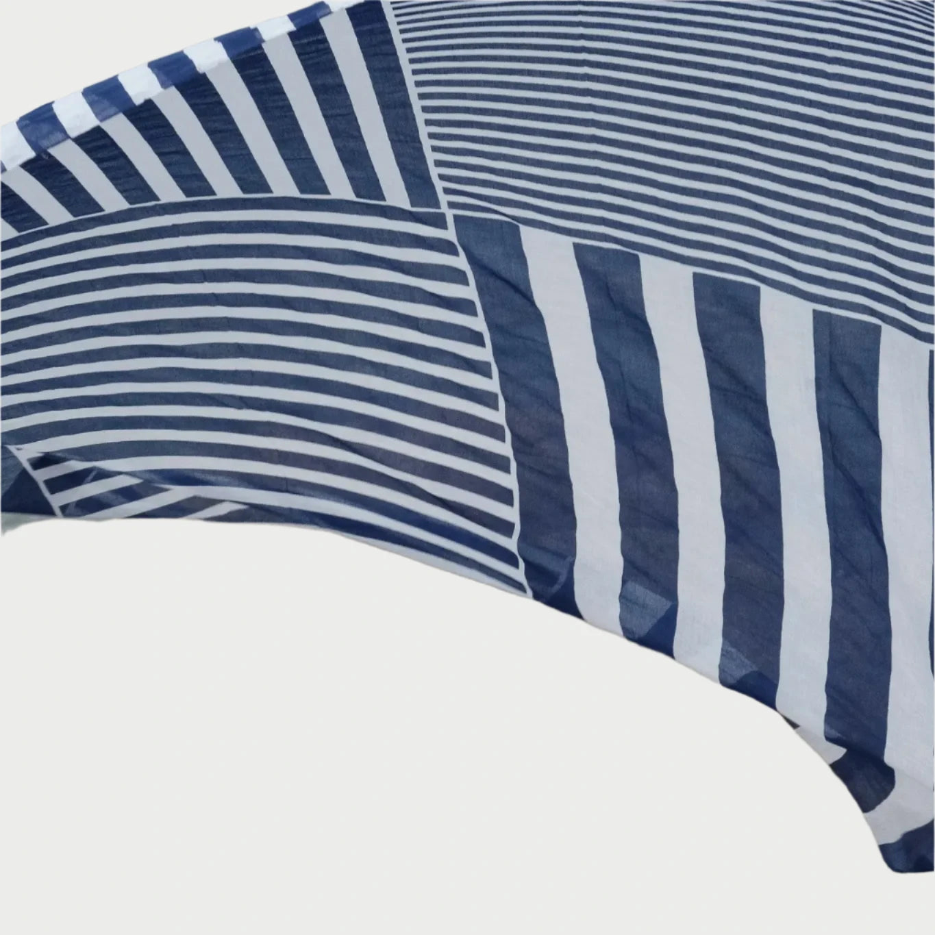 A close-up of a French designed Large Cotton Voile Scarf with blue and white stripes and patterns, stretching over a rocky surface. The fabric from Maison Lecomte Flament shows both curved and straight lines, creating an interesting visual contrast with the rough texture of the rocks below.