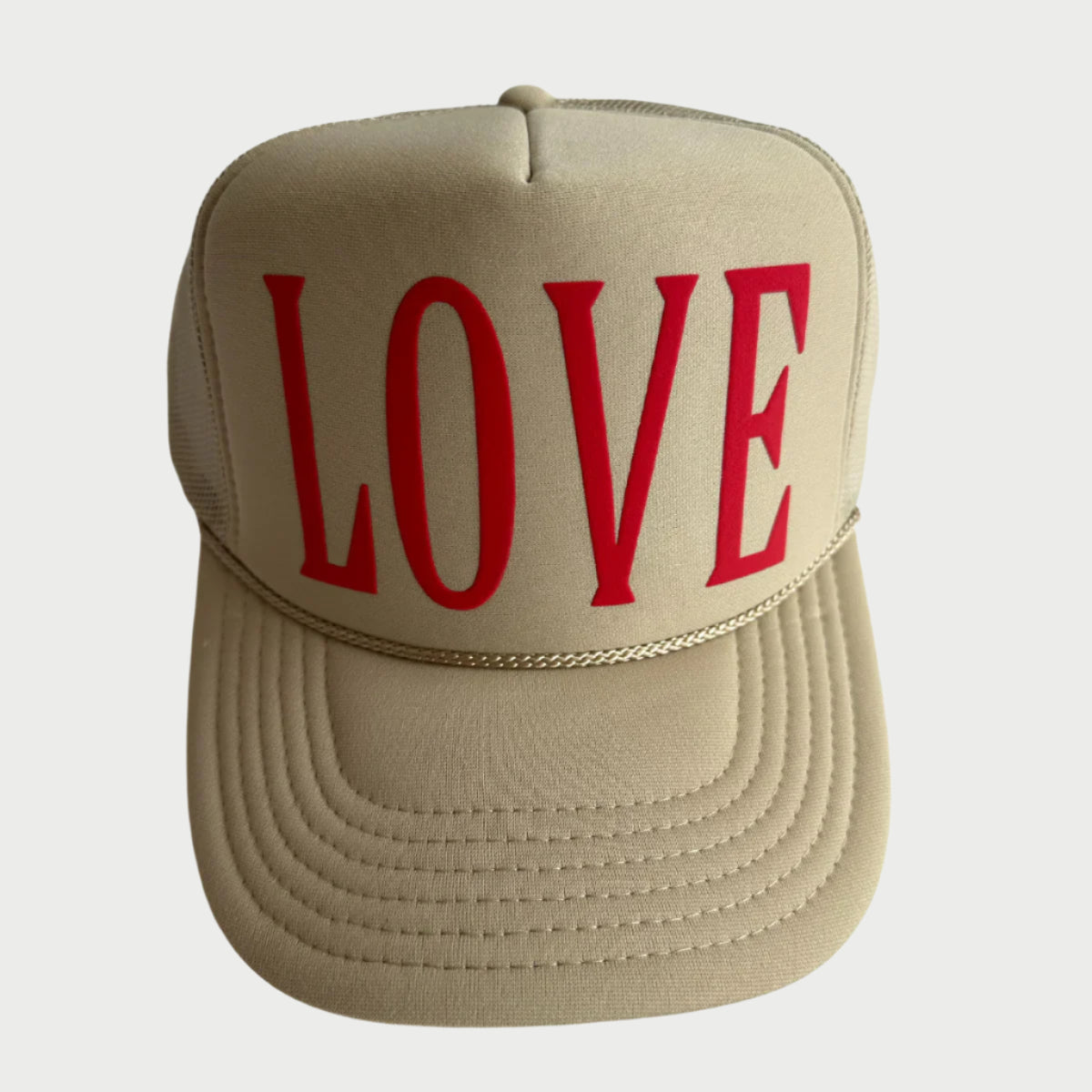 The Love Trucker Hat by LOCAL BEACH is an adorable beige hat with "LOVE" in bold red on the front, a mesh back, and a braided rope across the brim—ideal for a beach day.