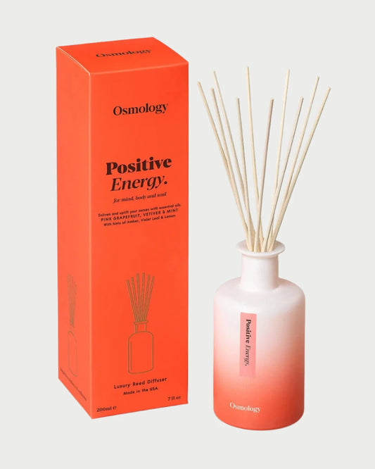 The Osmology Reed Diffuser, perfect for aromatherapy lovers, features a white-to-red gradient bottle complemented by wooden reeds. Its upright box echoes this striking design and underscores its vegan and cruelty-free attributes along with the brand information.