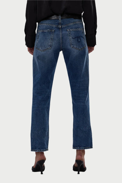 Rear view of a person wearing R13 Romeo Jeans, featuring a mid-rise and straight-leg design with a frayed hem, paired with black heeled sandals against a plain gray background. Crafted from 100% cotton, these jeans epitomize effortless style.