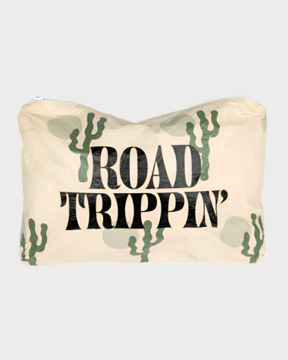 The LOCAL BEACH Printed Pouch- Beach is a beige Tyvek fabric pouch featuring bold black "ROAD TRIPPIN'" text and green cactus illustrations. It's stylish, water-resistant, and perfect for organizing your beach adventures.