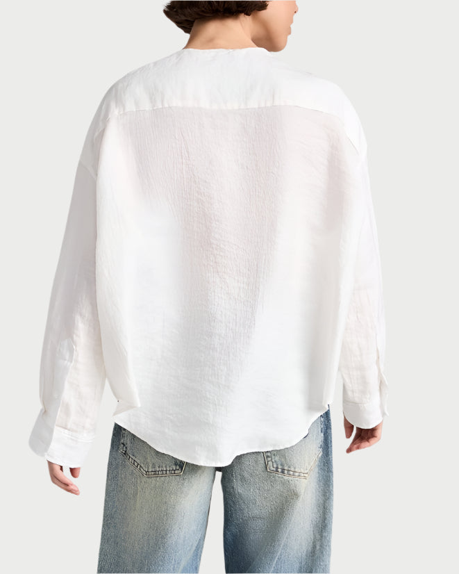 From the back, someone is wearing an R13 Twisted Neck Shirt, a loose-fitting, white long-sleeve made from Japanese crinkle lyocell fabric, along with faded blue jeans.