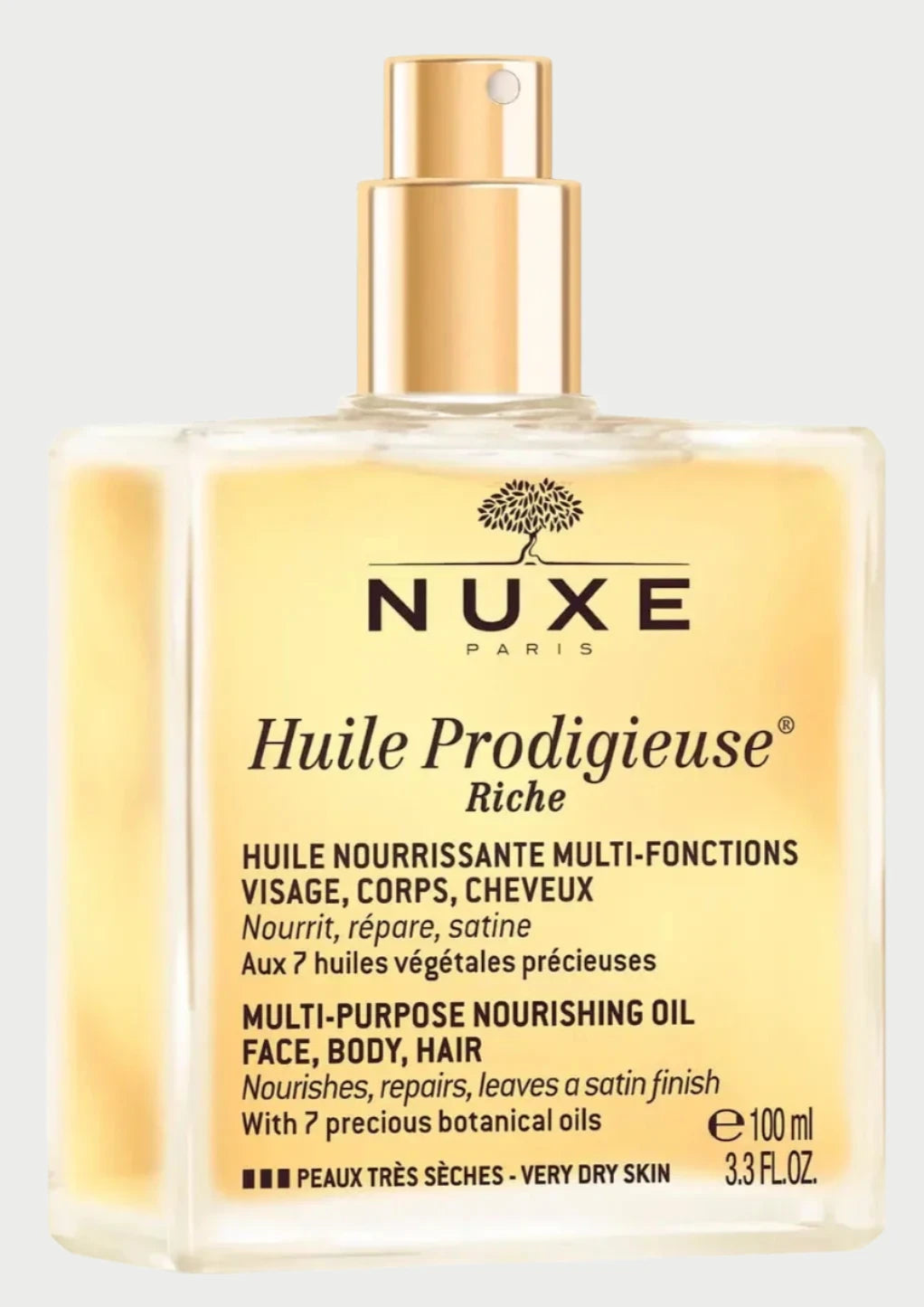 A rectangular, transparent bottle with a golden cap containing NUXE Huile Prodigieuse Riche, a multi-purpose dry oil for face, body, and hair. The bottle displays product details and claims to nourish, repair, and leave a satin finish, formulated with 7 botanical oils.