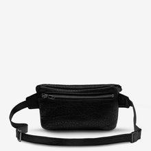 Load image into Gallery viewer, A black faux leather Belt Bag with a textured pattern from Status Anxiety. The bag features a front zipper pocket with gunmetal hardware, an adjustable waist strap, and a top main compartment. The bag is displayed on a plain, light-colored background.