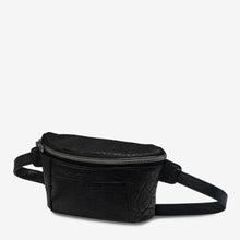 Load image into Gallery viewer, A black lamb skin leather Belt Bag with a textured surface by Status Anxiety. The bag features gunmetal hardware, a main compartment with a zipper closure, an adjustable strap, and a smaller front pocket also with a zipper closure. The background is plain white.