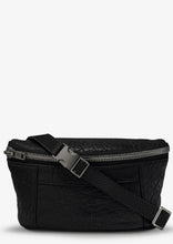 Load image into Gallery viewer, A black lamb skin leather Belt Bag with a textured surface, featuring gunmetal hardware, including a silver zipper on the front and a buckle on the adjustable strap. The compact and stylish Status Anxiety cross body bag has two small pockets on the front.