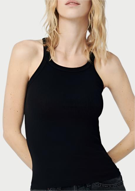 A woman with shoulder-length blond hair wearing a fitted black Ribbed Tank from RE/DONE and dark jeans stands against a plain white background. She gazes confidently at the camera with a slight natural pose.