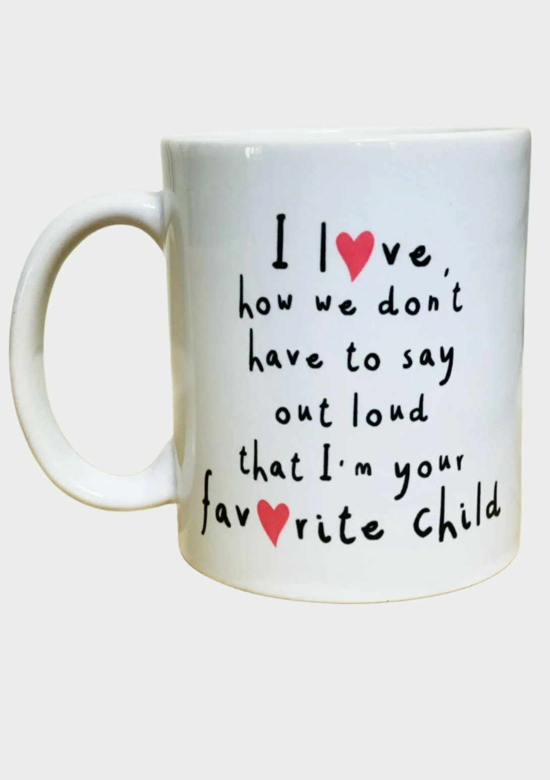 A white coffee mug on a light wooden surface with the text: "I ❤️ love, how we don't have to say out loud that I'm your fav❤️rite child." The words "love" and "favorite" both have red heart symbols replacing the letter 'o'. Perfect as a thoughtful Mother's Day gift idea, the Favorite Child Mug by 365 Printing Inc adds humor and warmth.